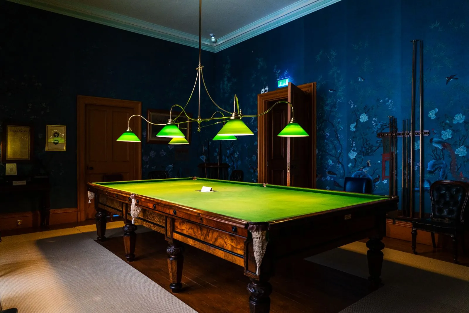 Bàn snooker dưới đèn chao xanh trong phòng tường xanh đậm